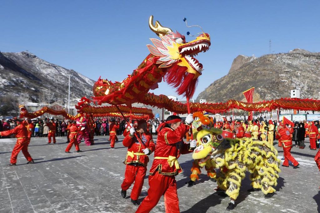 Chinese dragon dance and lion dance performed outdoors.